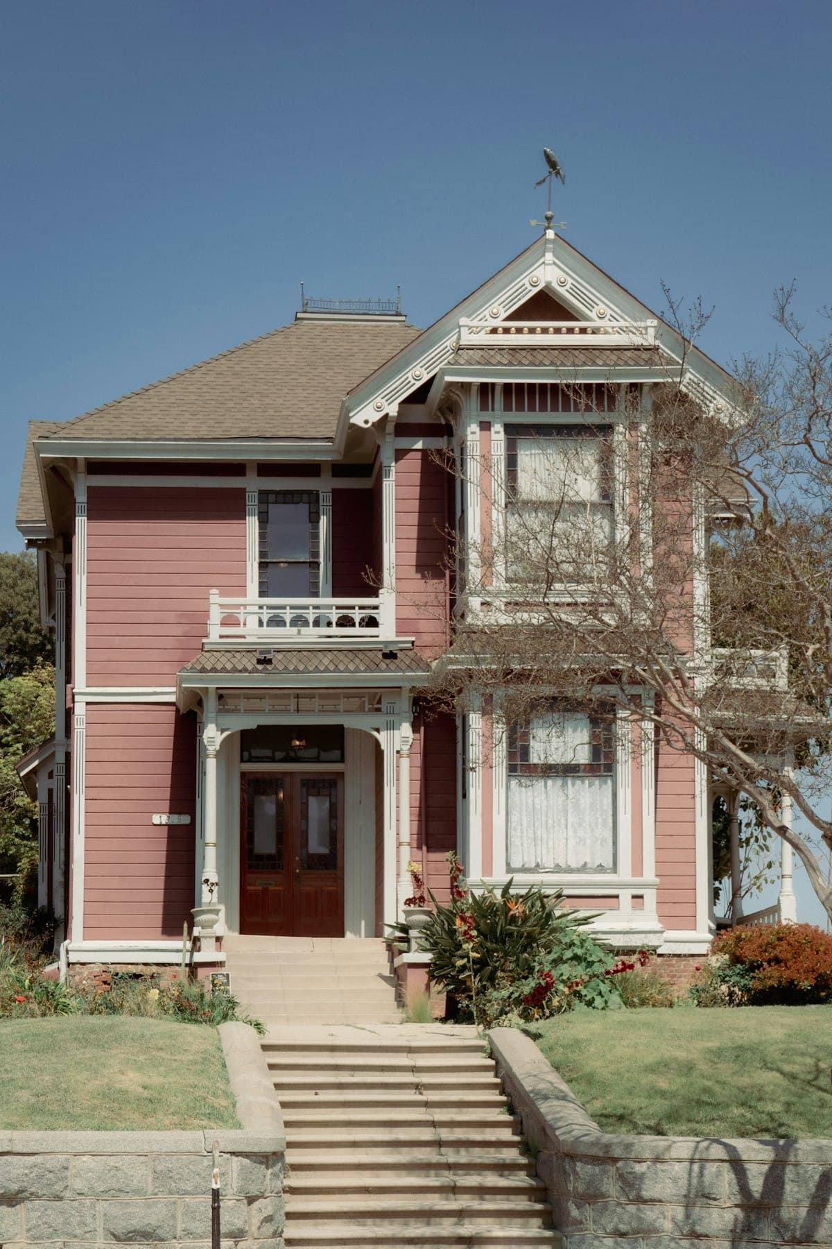A pink Victorian home with decorative white trim