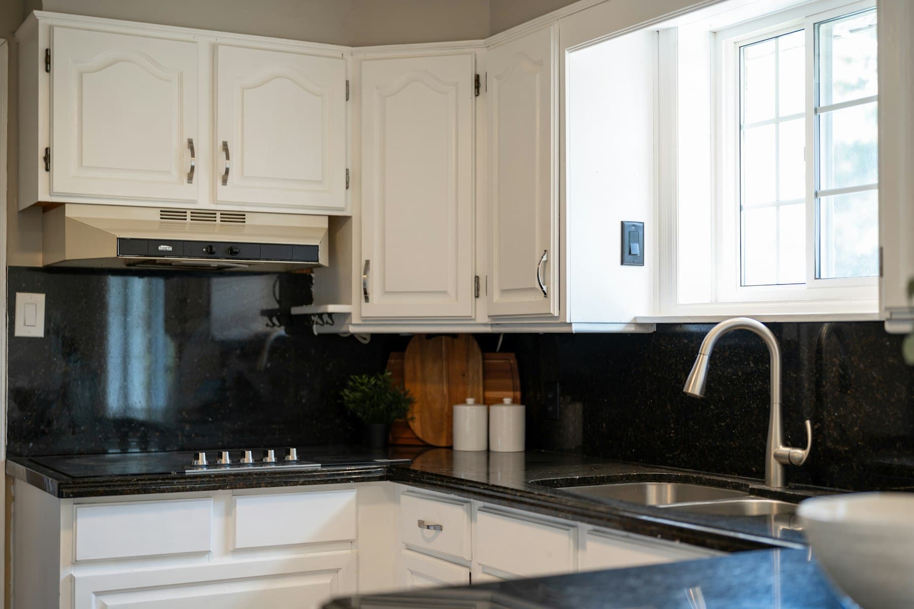 A modern kitchen with painted white cabinetry and dark countertops