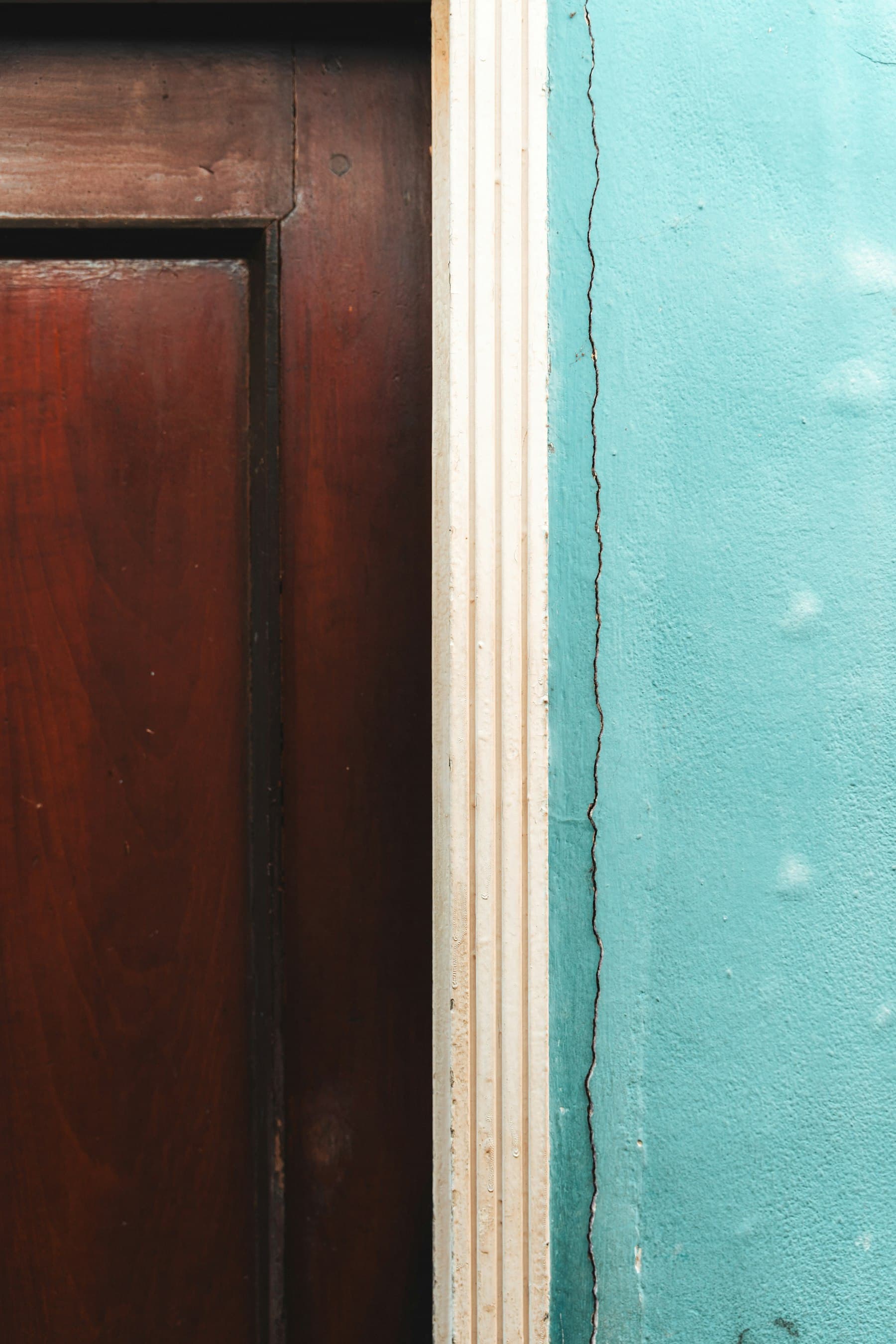 Close-up detail of a painted wood door and trim against a colored wall