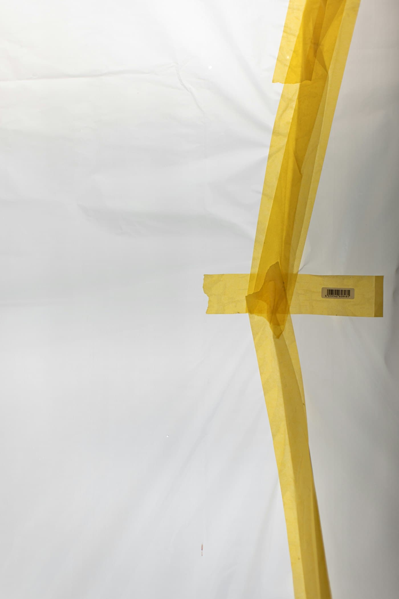 Close-up of crisp yellow masking tape lines on plastic sheeting
