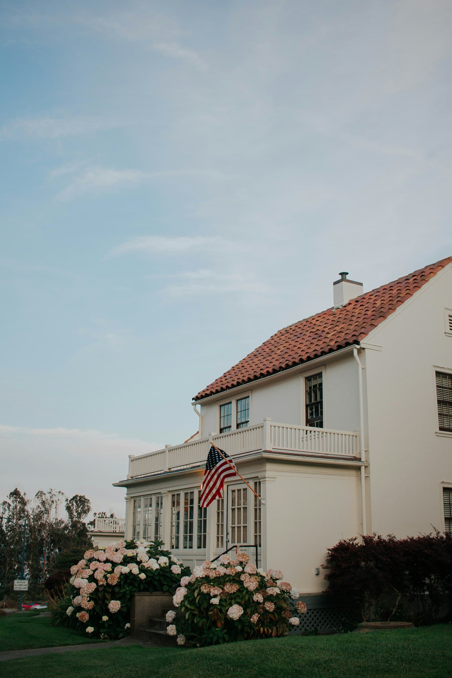 A cream Mediterranean-style American home exterior with a tile roof and American flag