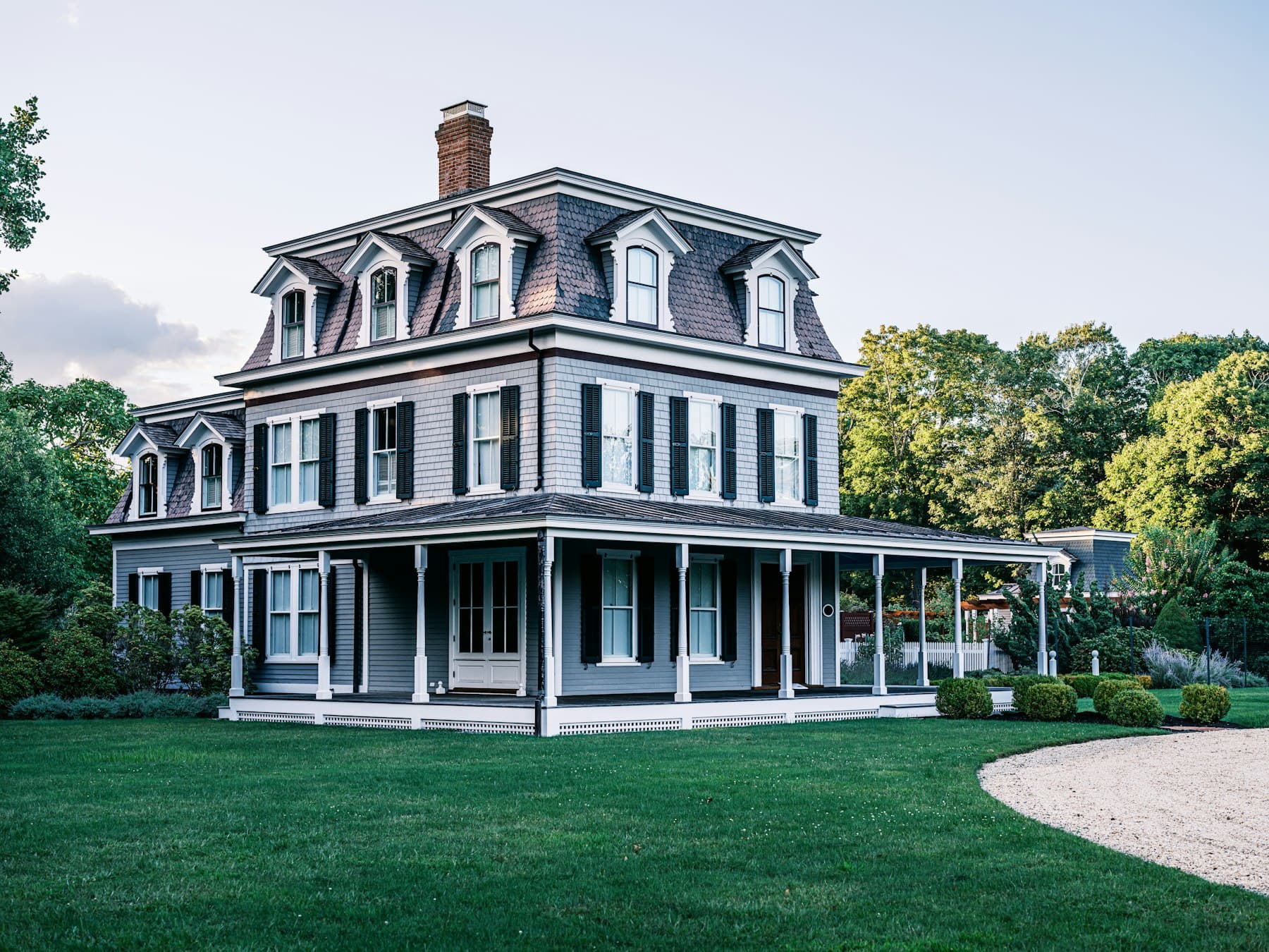 A gray Victorian-style home with a wraparound porch